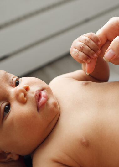 African newborn baby holding mother finger. Little baby touching mom hand and looking at her eyes. Innocence, security, purity, motherhood, new life, love and happiness concept.